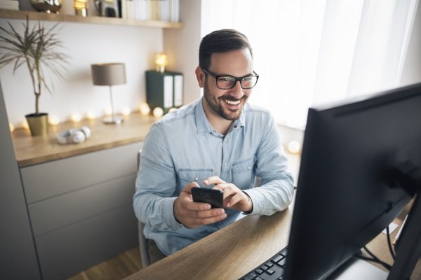 Mann bei der Zeiterfassung im Homeoffice über Smartphone